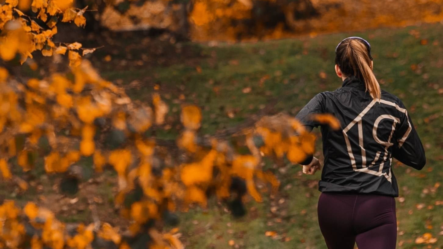 A woman running in Power Woman apparel during autumn