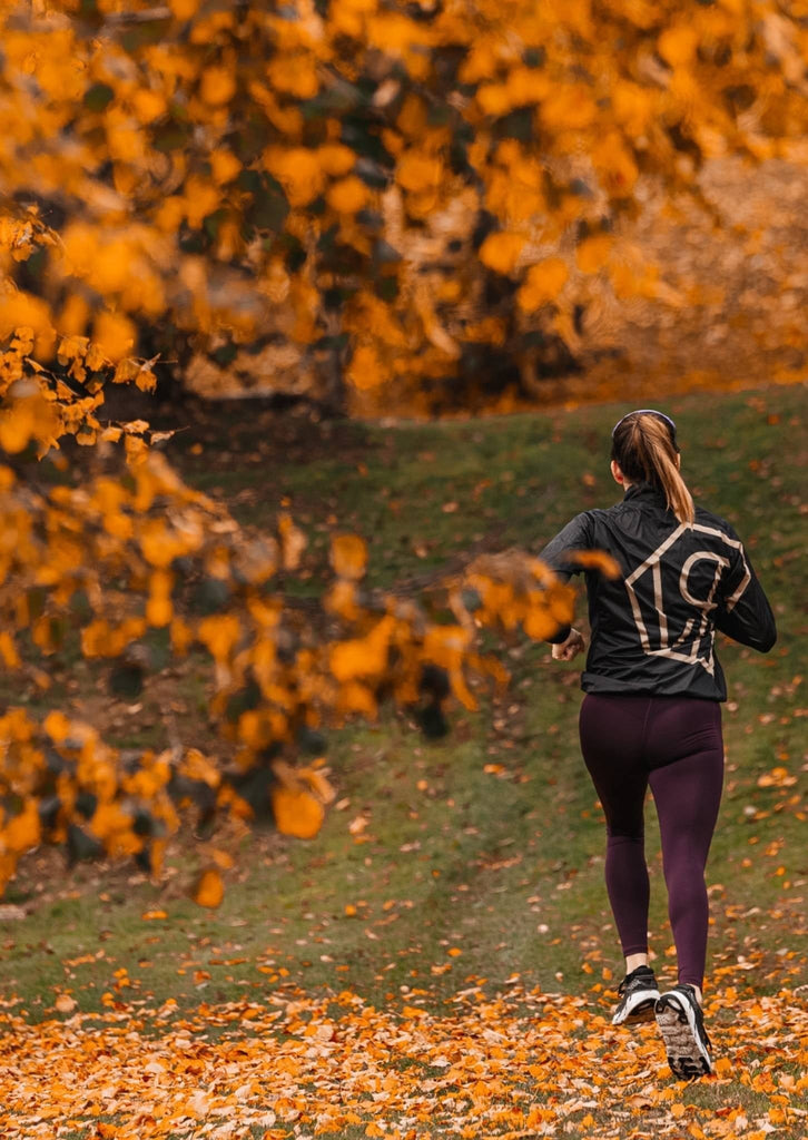 A woman running in Power Woman apparel during autumn