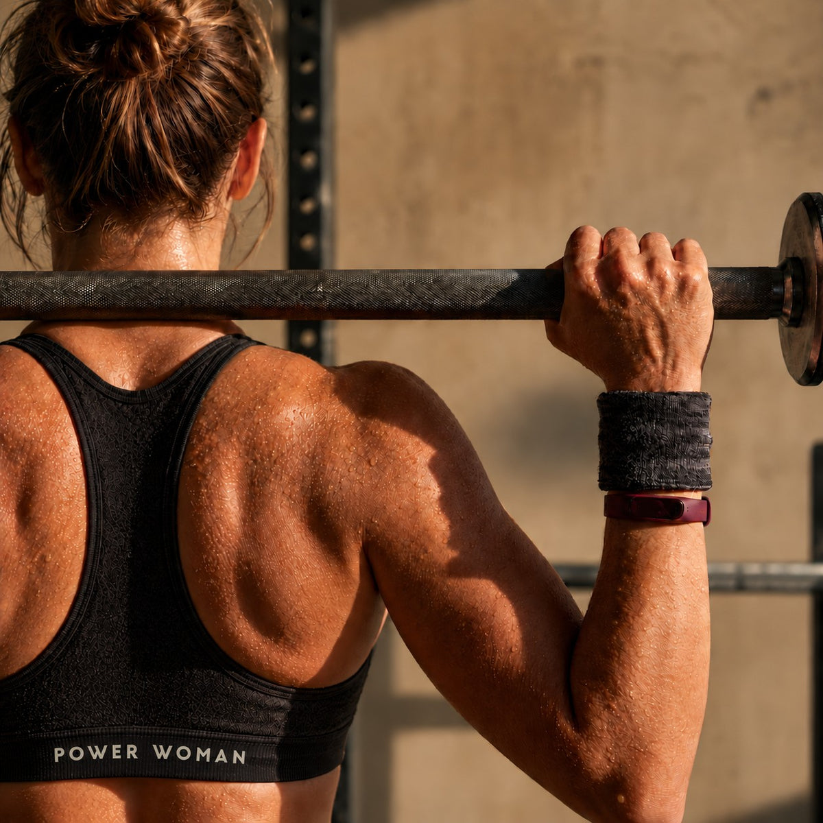 Woman holding a barbell across her shoulders, wearing Power Woman.